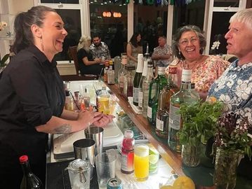 Bartender laughing with two customers at a lively bar counter.
