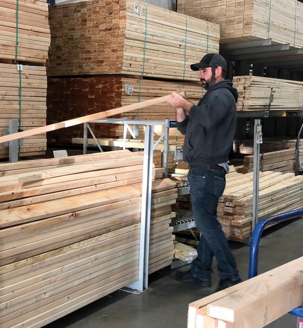 Man selecting lumber in a hardware store aisle.