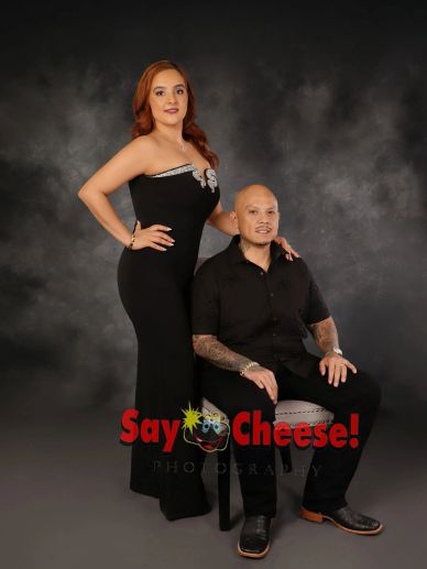 Couple posing for formal portrait against dark backdrop.
