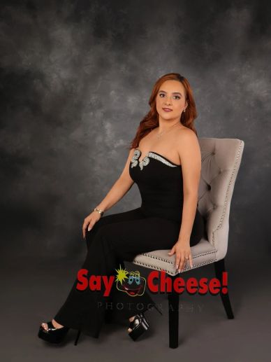 Woman in black dress sitting on a chair.