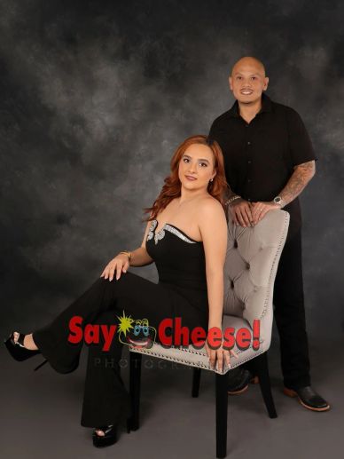 Couple posing with elegant attire against a dark backdrop.