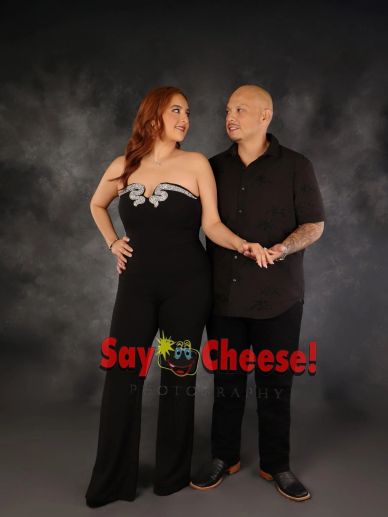 Couple posing together, holding hands and smiling at each other.