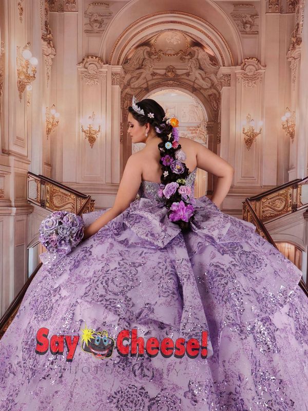 Woman in a glittery lavender gown with floral hair decoration.