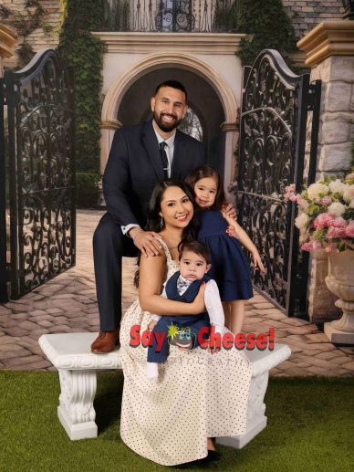 Happy family posing on a bench with garden backdrop.