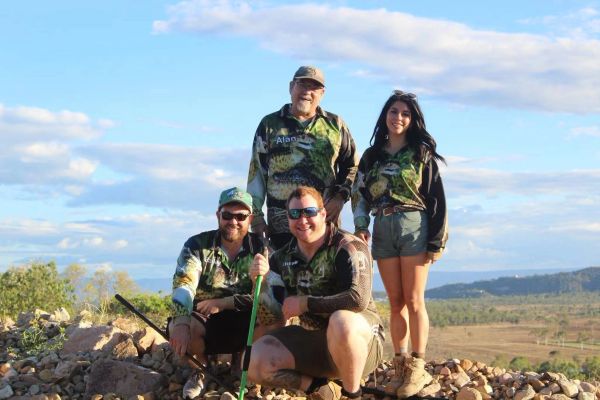 Group of four people posing outdoors on rocky terrain.