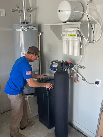 A plumber in blue working on a filtration system