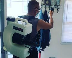 Man wearing a Fogger inside a room, spraying disinfectant & sanitizer.