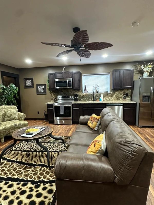 Cozy kitchen and living area with animal print rug and brown leather sofa.