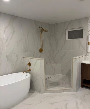 Modern bathroom with marble tiles and gold fixtures. By JTAL Home