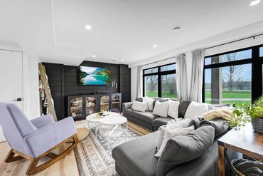 Bright modern living room with large windows and cozy seating.