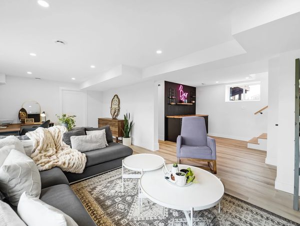 Bright, modern living room with gray sofas, a cozy throw, and a small bar area.