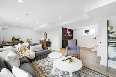 Bright, modern living room with gray sofas, a cozy throw, and a small bar area.