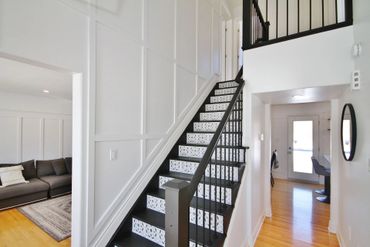 Modern staircase with patterned risers and black railings in a bright home.