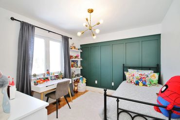 Bright kid's bedroom with toys, a study desk, and a bold green accent wall.