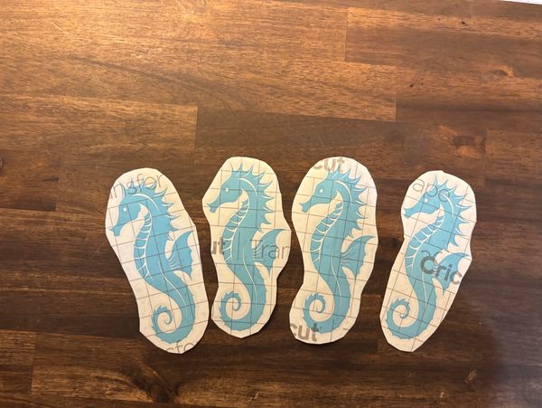 Four blue seahorse stickers on a wooden surface.