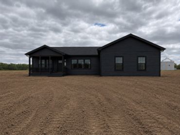 Dark Brunswick home with black windows, trim, and modern barndominium-style accents.
