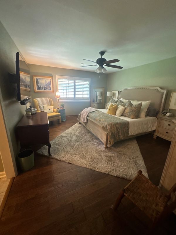 Cozy bedroom with a large bed, plush rug, and a yellow armchair by the window.