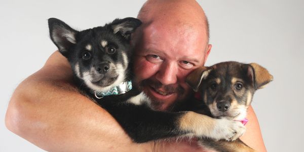 Man hugging two adorable puppies.