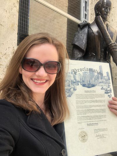Image of Founder, Mary Mecham, holding a Proclamation for Disability Book Week
