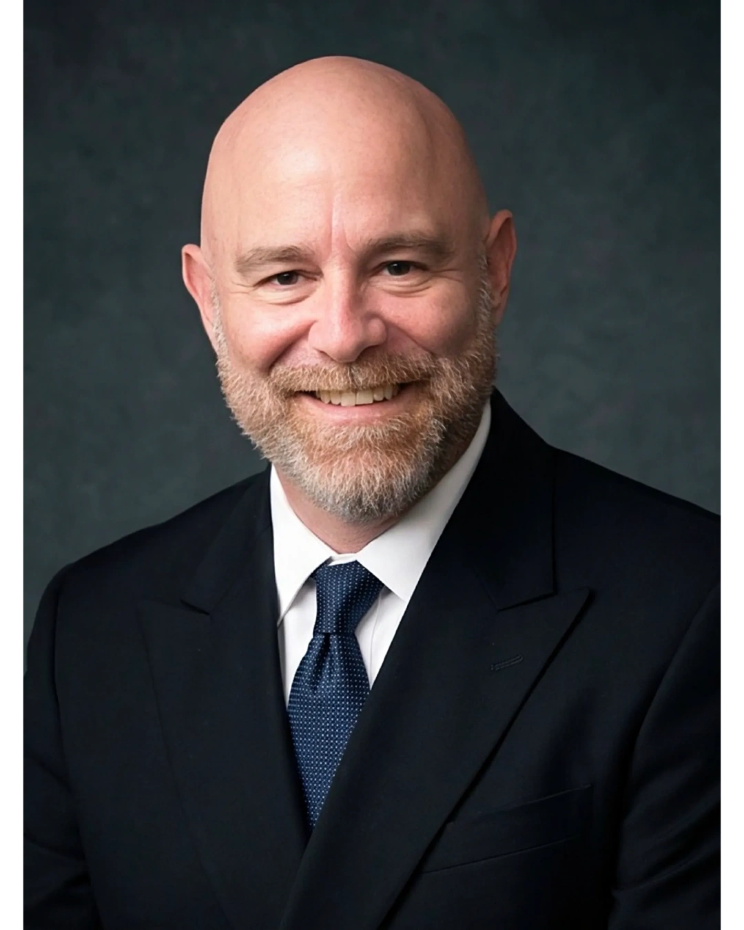 Smiling bald man in a suit and tie.