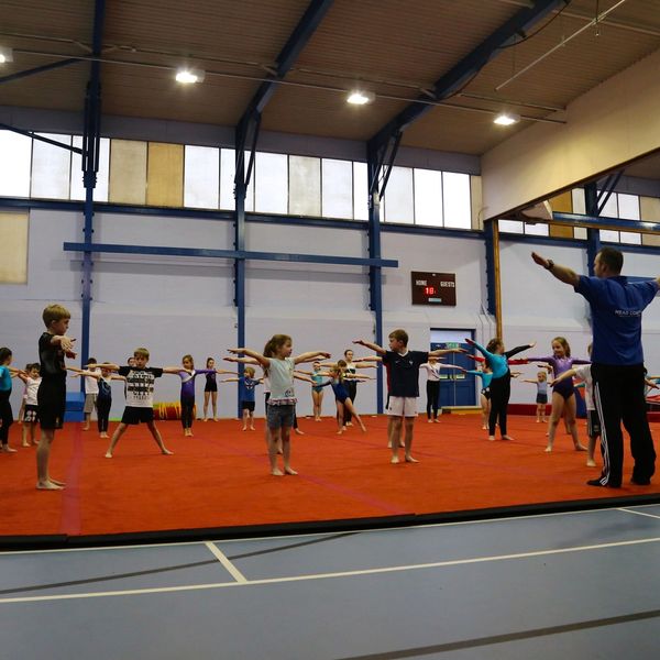 A gymnastics instructor standing in front of a children class