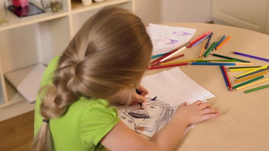 Child drawing with colored pencils at a table.