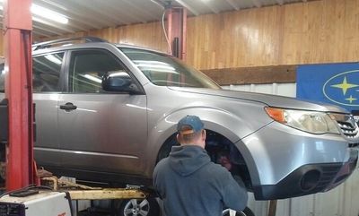 Picture of a Subaru lifted in a repair shop.