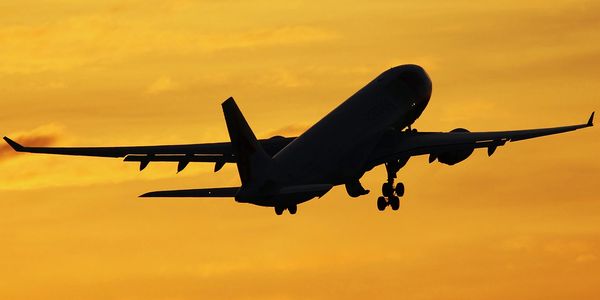 Airplane silhouette flying against a golden sunset sky.