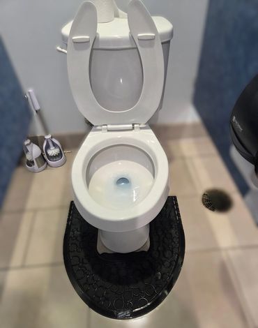 Clean white toilet with open seat and black floor mat in a bathroom.