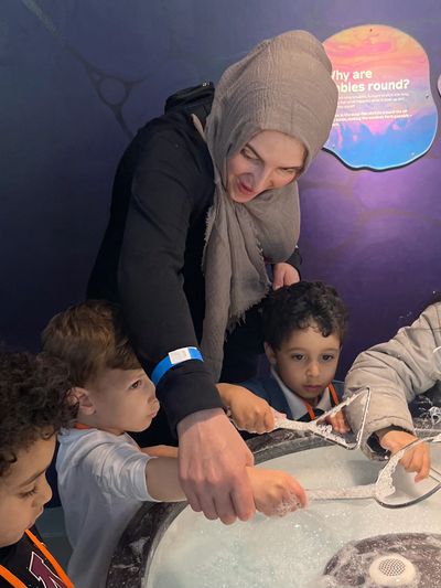 Woman guides kids in bubble play at exhibit.