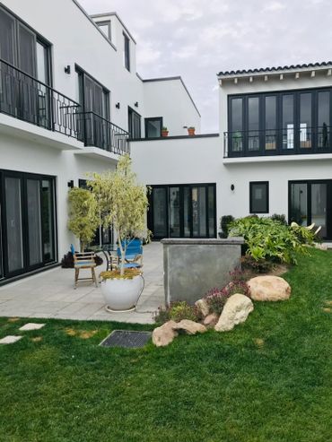 Modern white house with black-framed windows and lush green garden.