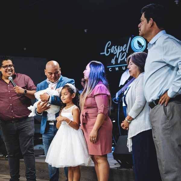 Family gathered on stage for a baby dedication ceremony at Gospel of Peace Church.