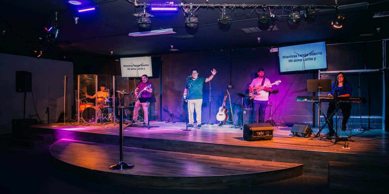 Band performing on stage with vibrant purple and blue lighting.