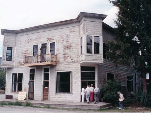 Old, weathered two-story building with people outside.
