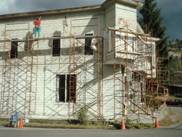 Workers painting a two-story house using scaffolding.