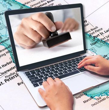 Hand using a stamp on a laptop screen with hands typing on keyboard.
