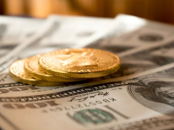 Golden bitcoins stacked on US hundred-dollar bills.