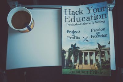 Book titled 'Hack Your Education' beside a cup of coffee on a tray.