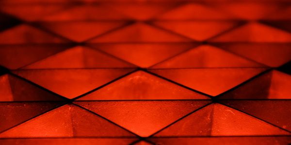 Close-up of an illuminated red geometric pattern with pyramid shapes.