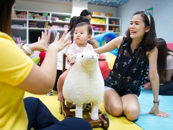 Mother and baby playing in a colorful playroom.