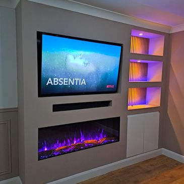 Modern media wall setup with a wall-mounted TV, electric fireplace, storage, & lighting.