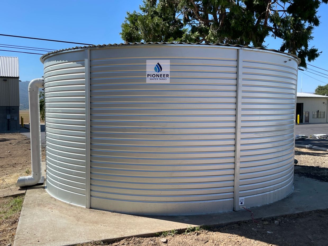 A large silver Pioneer water tank outdoors with a clear blue sky.