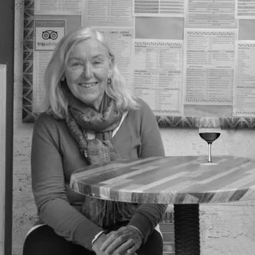 Smiling woman sitting at a wooden table with a wine glass illustration.