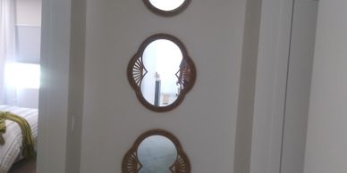 Three decorative mirrors with wooden frames mounted vertically on a white wall.