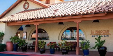 Exterior view of La Brasserie Bistro & Bar with potted plants and arched windows.