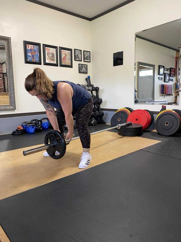 Woman preparing to lift a barbell in a gym.