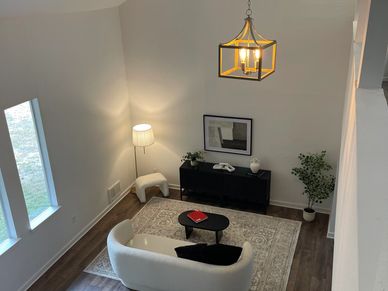 Modern living room with curved white chairs, a patterned rug, and warm lighting.