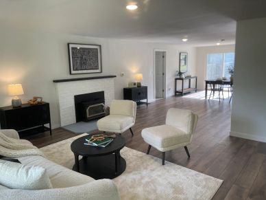 Modern living room with white furniture and wood flooring.