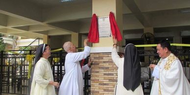 Religious figures unveiling a plaque inside a building.