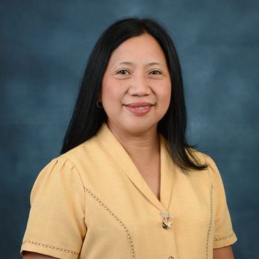 Woman in yellow blouse smiling against a blue background.